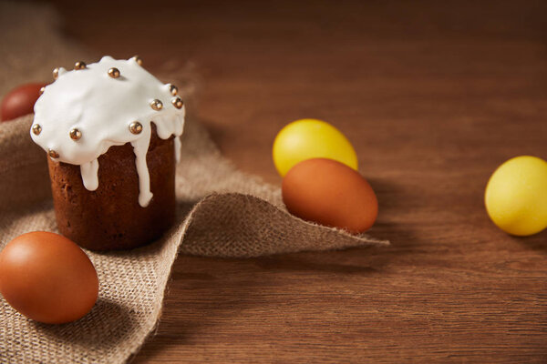 painted chicken eggs and traditional easter cake decorated with sprinkles on sackcloth