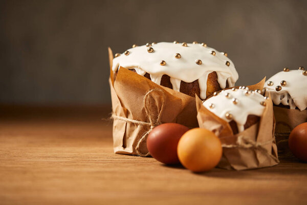 delicious easter cakes with sprinkles and painted chicken eggs on wooden surface with copy space