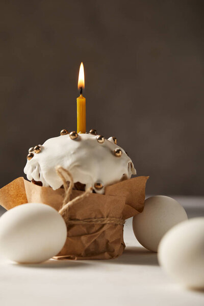 selective focus of delicious easter cake with burning candle and chicken eggs