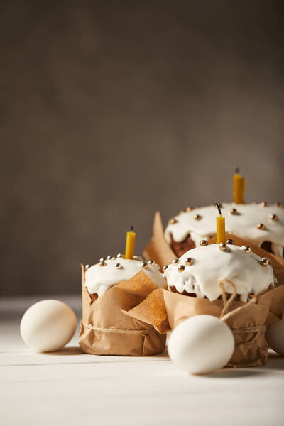 traditional easter cakes with candles and chicken eggs on white table with copy space