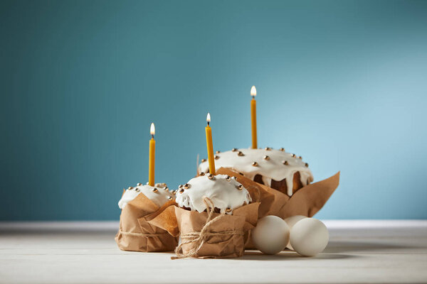 delicious easter cakes with candles and chicken eggs on turquoise