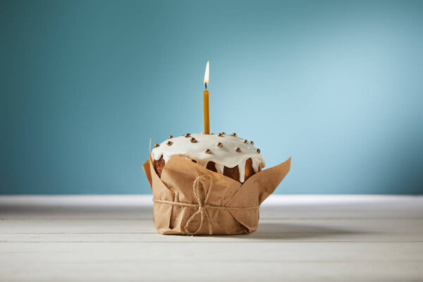 easter cake decorated with sprinkles and burning candle on turquoise