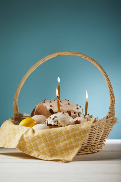 Easter cakes with chicken eggs and napkin in wicker basket on turquoise