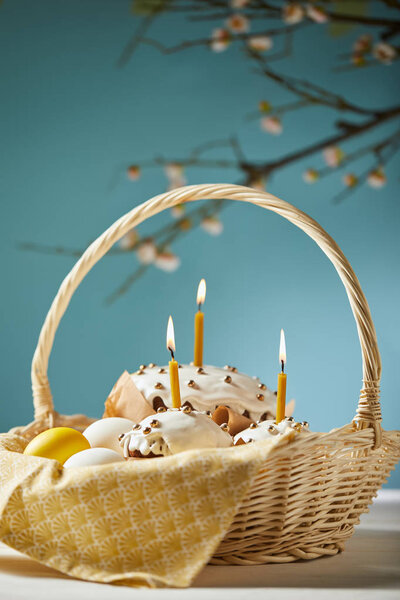 easter cakes with chicken eggs and napkin in wicker basket on turquoise