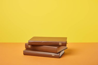 Brown books on bright orange surface isolated on yellow clipart
