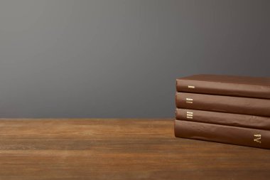Four brown books on textured wooden surface on grey clipart