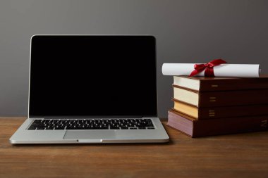 Boş ekran, kitap ve ahşap yüzey üzerinde diploma gri üzerinde izole laptop