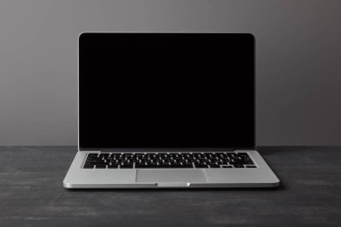 Gri üzerinde koyu dokulu yüzeyde boş ekran ile Laptop