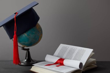 Küre, akademik kap, diploma ve gri açık kitap
