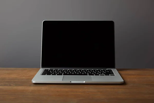 在棕色木质表面上有空白屏幕的笔记本电脑 在灰色上被隔离 — 图库照片