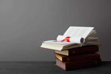 Gri üzerinde karanlık yüzeyde kırmızı kurdele ile kitaplar ve diploma