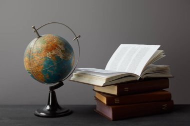 Old globe and books on dark surface on grey clipart