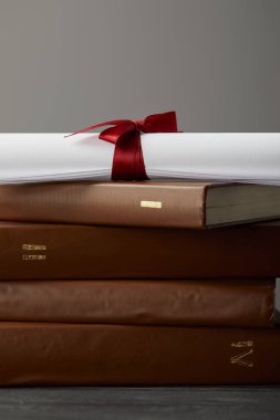 Brown books and diploma with red ribbon on grey clipart
