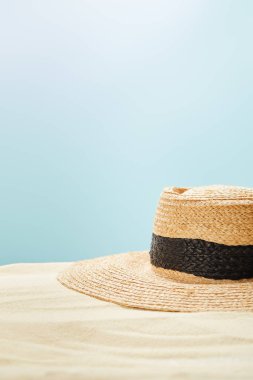 mavi üzerinde izole yaz aylarında altın kum üzerinde saman şapka seçici odak