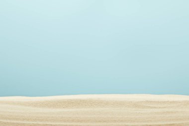 selective focus of golden and textured sandy beach isolated on blue clipart