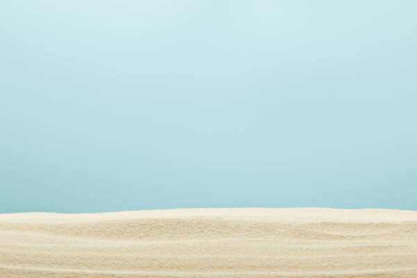 selective focus of golden and textured sandy beach isolated on blue