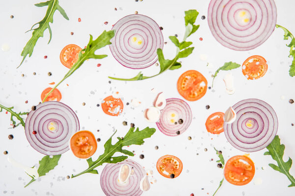 background with sliced tomatoes, red onions, garlic, arugula leaves and spices