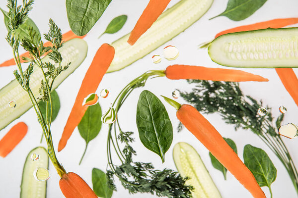 background with carrots, sliced cucumbers, spinach leaves and water bubbles