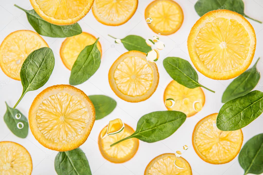 fresh juicy orange slices with green spinach leaves on grey background with water bubbles