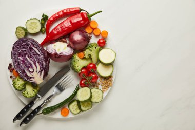 Top view of cutlery and fresh vegetables on white surface clipart
