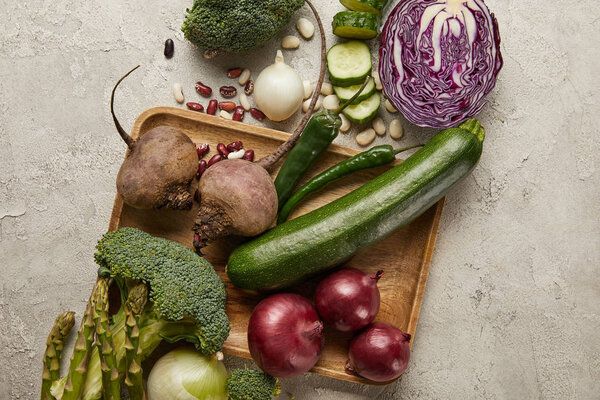 Top view of vegetables and beans on wooden tray