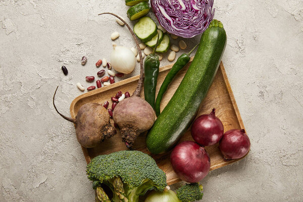 Top view of vegetables and beans on wooden tray
