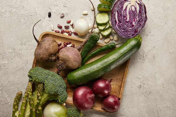 Top view of vegetables and beans on wooden tray