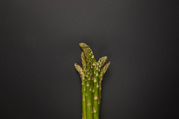 Top view of fresh green asparagus on black surface