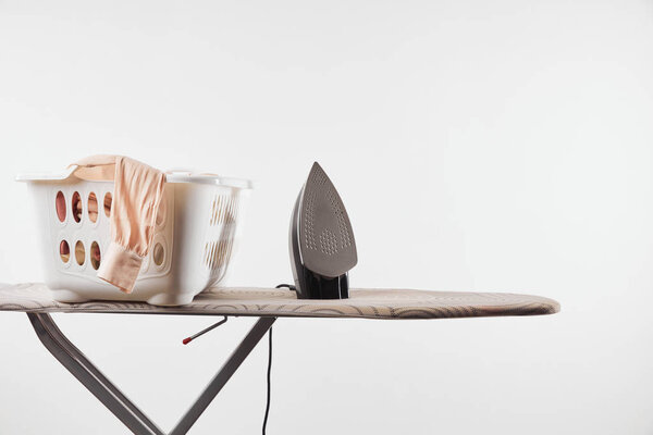 Ironing board, laundry basket and iron isolated on white