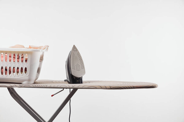 Ironing board, laundry basket and iron isolated on white