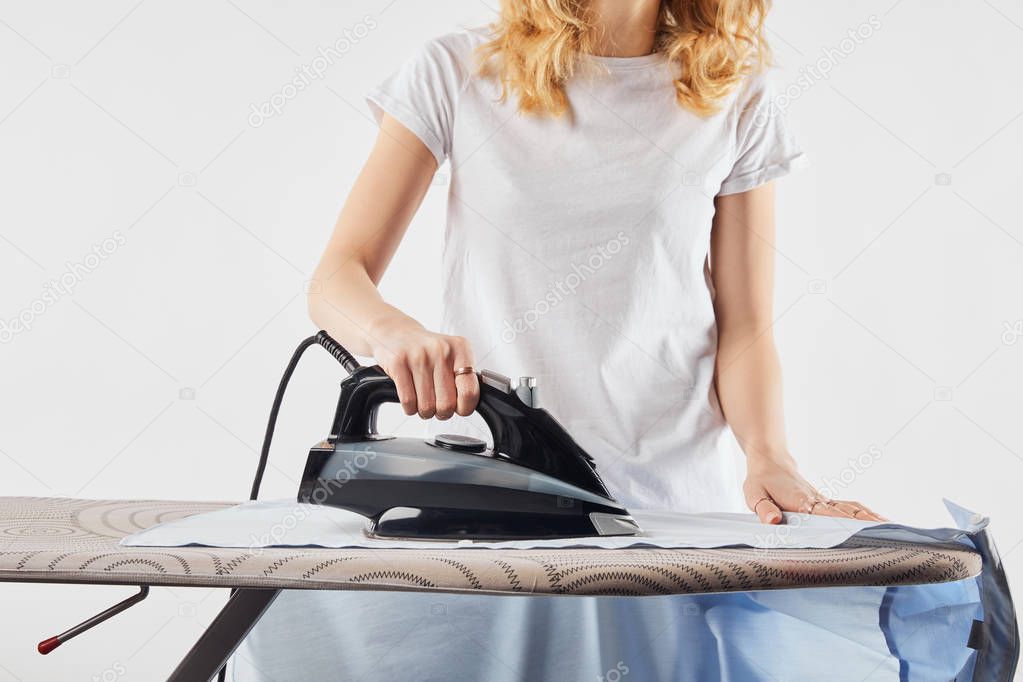 Cropped view of girl ironing blue shirt isolated on grey