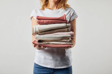 Cropped view of woman holding folded ironed clothes isolated on grey clipart