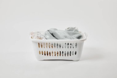 Gri üzerinde kirli giysiler ile beyaz plastik çamaşır sepeti