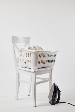 White chair, laundry basket with clothes and iron on grey clipart