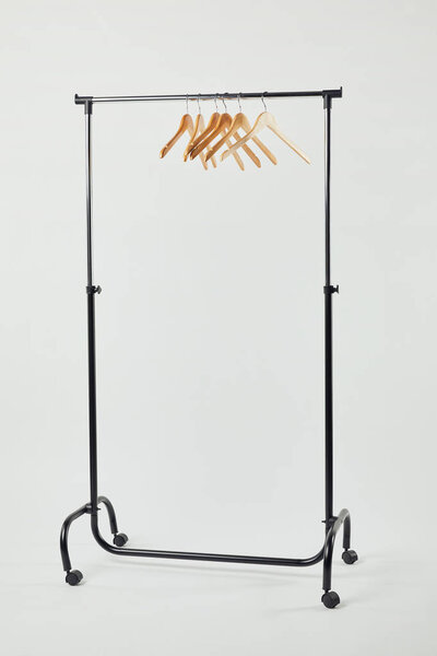 Черная стальная прямая стойка с деревянными вешалками на сером
