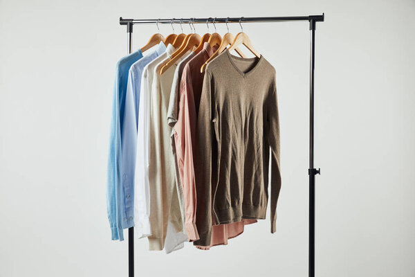 Straight rack, wooden hangers and male clothes isolated on grey