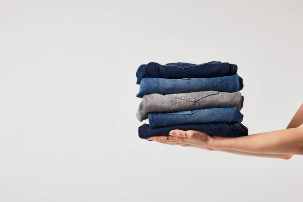 Cropped view of girl holding ironed pants isolated on white