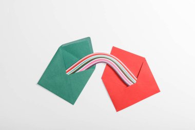 top view of green and red envelopes with multicolored rainbow on grey background clipart