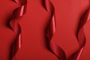 close up of curved silk red ribbons on red background clipart