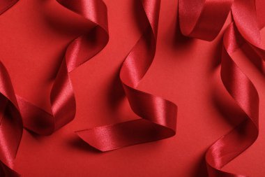 close up of curved satin red ribbons on red background clipart