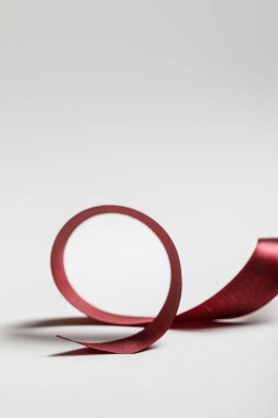 satin curved burgundy ribbon on grey background