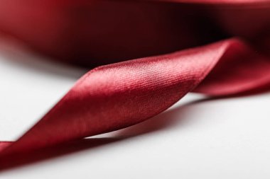 close up of silk curved burgundy ribbon on grey background