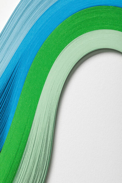 close up of wavy blue and green paper lines on grey background
