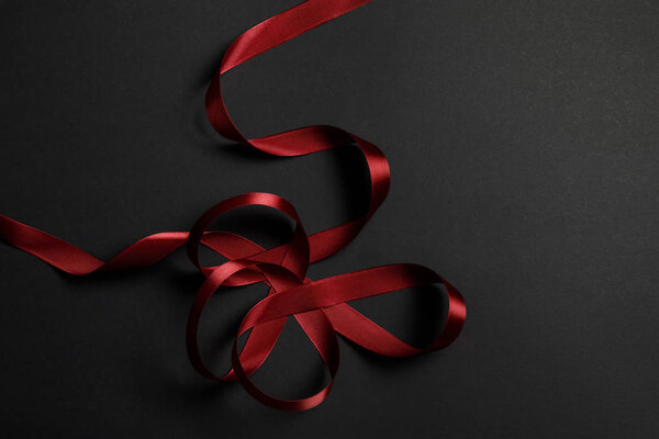 верхний вид красной атласной волнистой ленты на черном фоне с копировальным пространством
