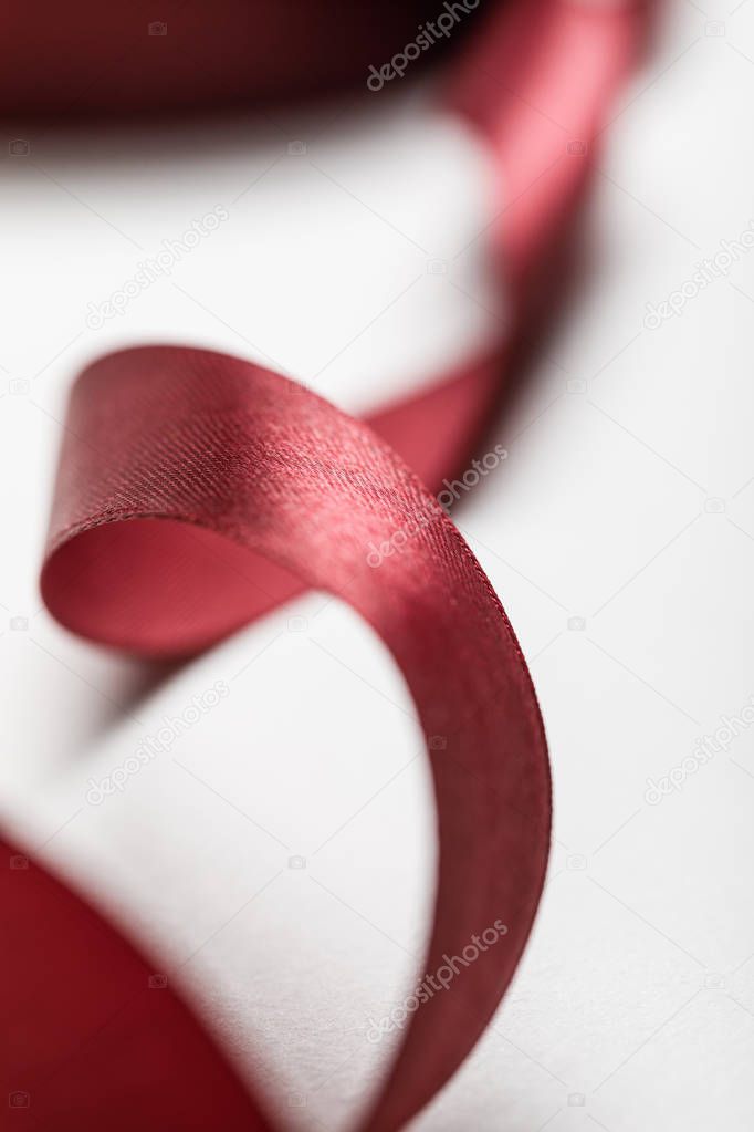 close up of silk wavy burgundy ribbon on grey background