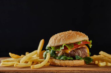 peynir ile lezzetli et Burger, yeşillik ve susam yakın Fransız patates üzerinde izole siyah