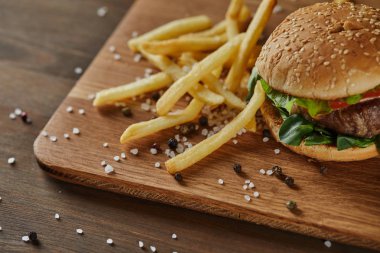 Ahşap Doğrama tahtasında dağınık tuz ve karabiber ile lezzetli et Burger ile taze altın patates kızartması