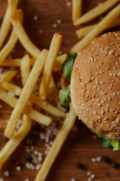 top view of delicious burger with sesame on bun and french fries with salt