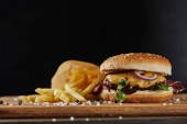 sůl, hranolky a vynikající Burger s masem na dřevěném povrchu izolovaného na černém