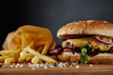 tuz, patates kızartması ve ahşap yüzeyde et ve peynir ile lezzetli burger seçici odak